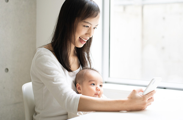 抱っこ紐でスマホを使う親